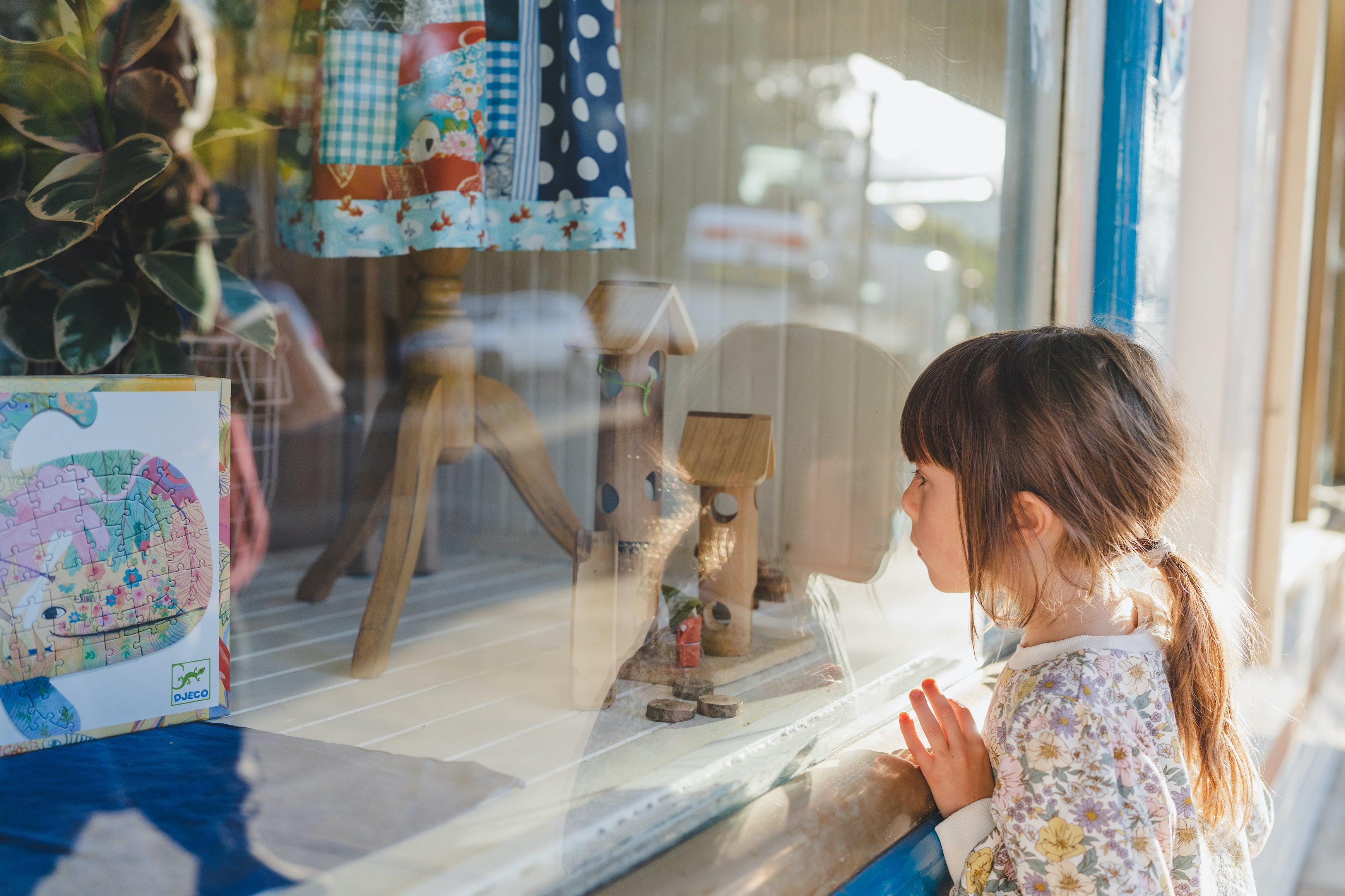 Little girl looks through the window of a toy shop in Bellingen NSW